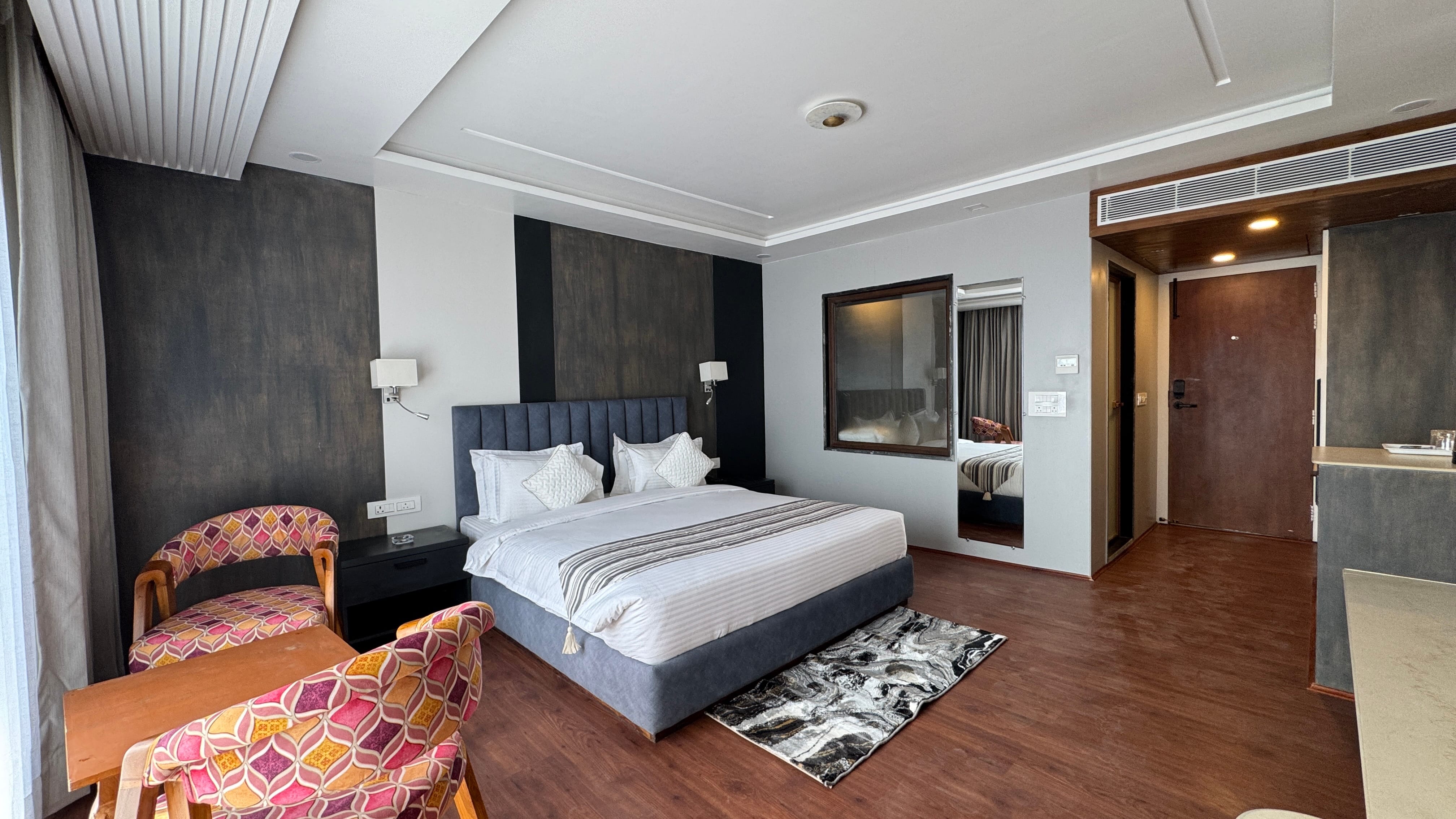 Double Deluxe Premium room with elegant blue headboard and dark accent wall at Emroz by Kings Resort