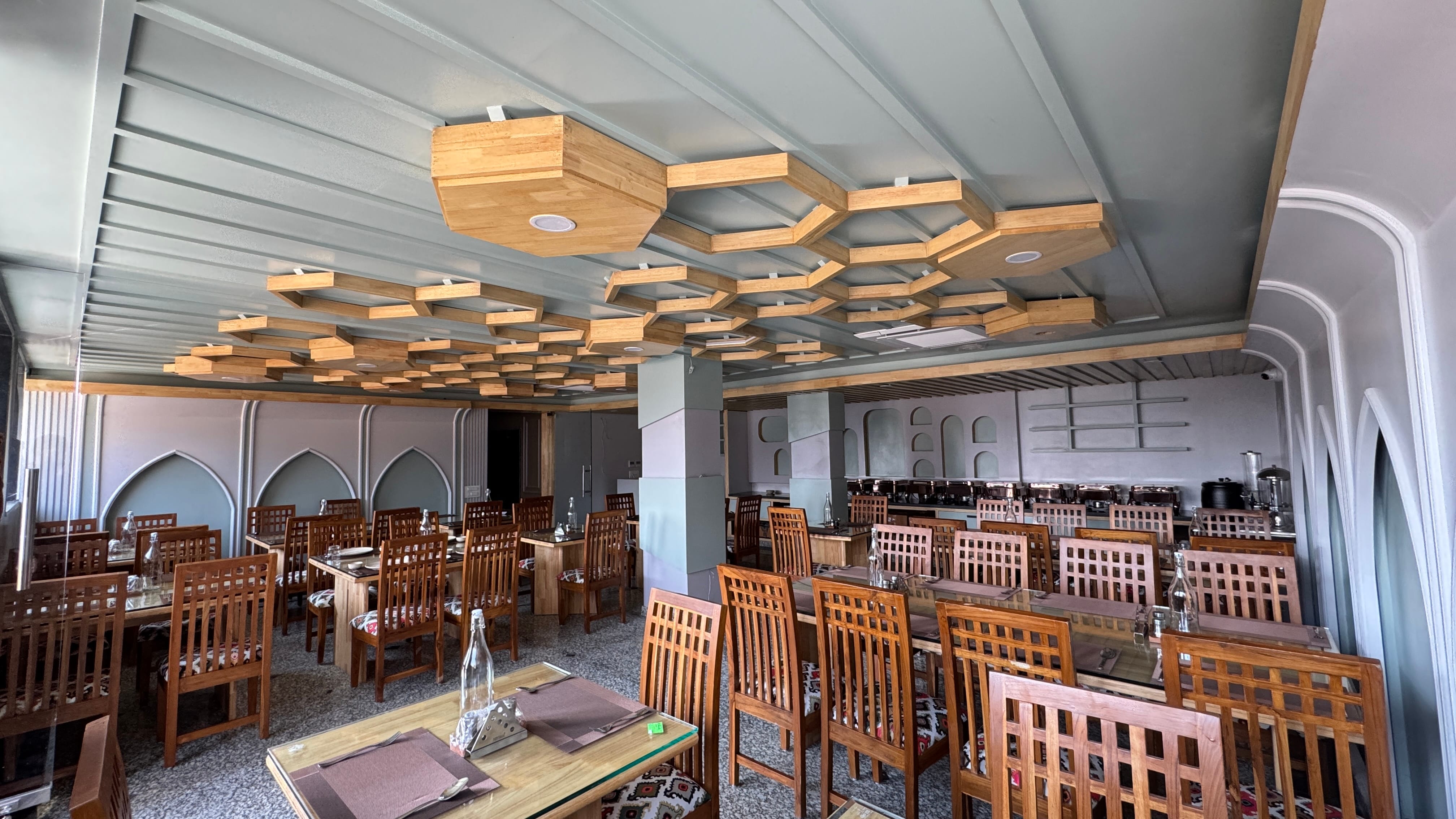 Spacious restaurant with hexagonal wooden ceiling and Kashmiri arch details