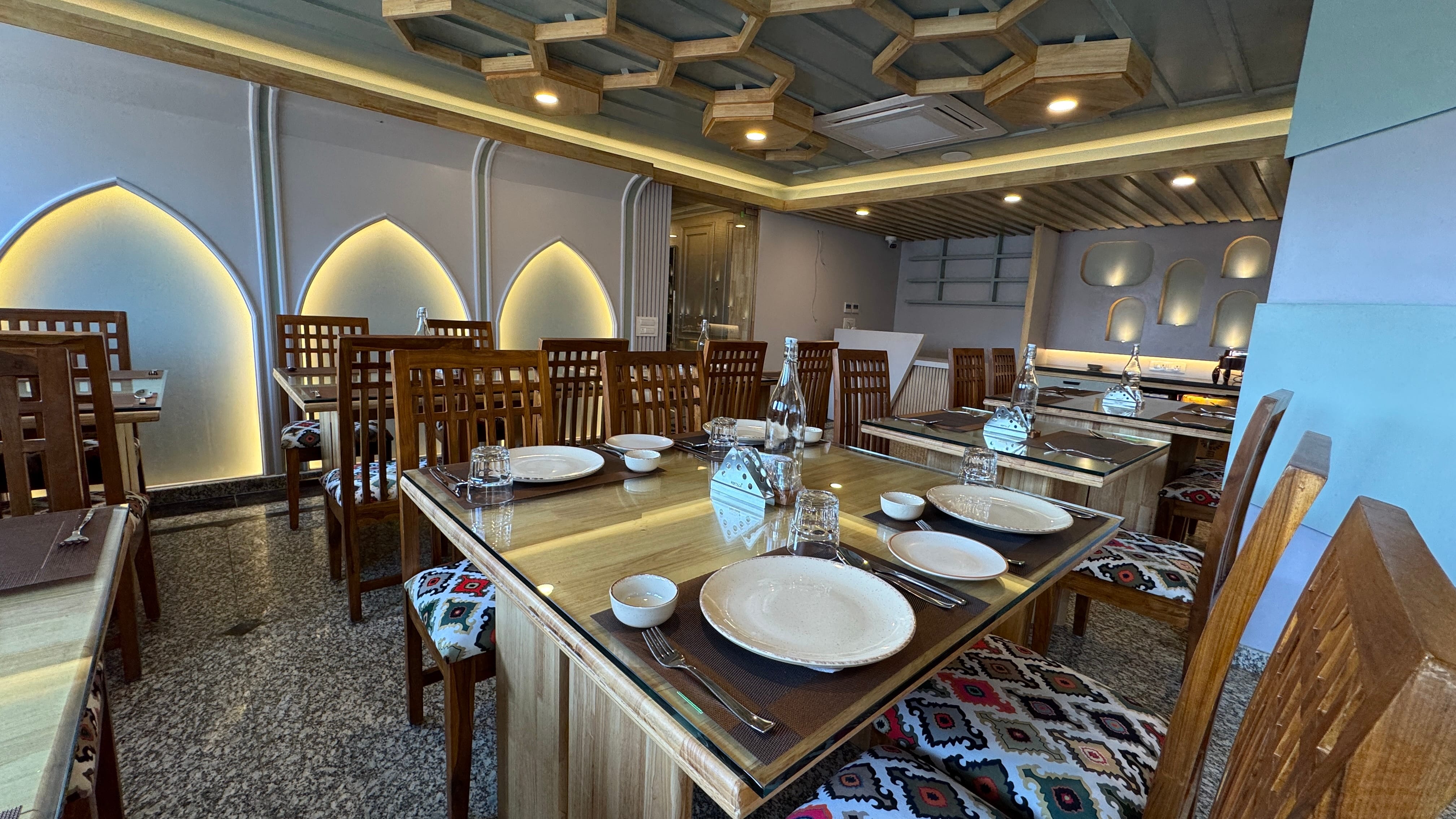 Restaurant table setting with Kashmiri cushioned chairs and arch wall niches