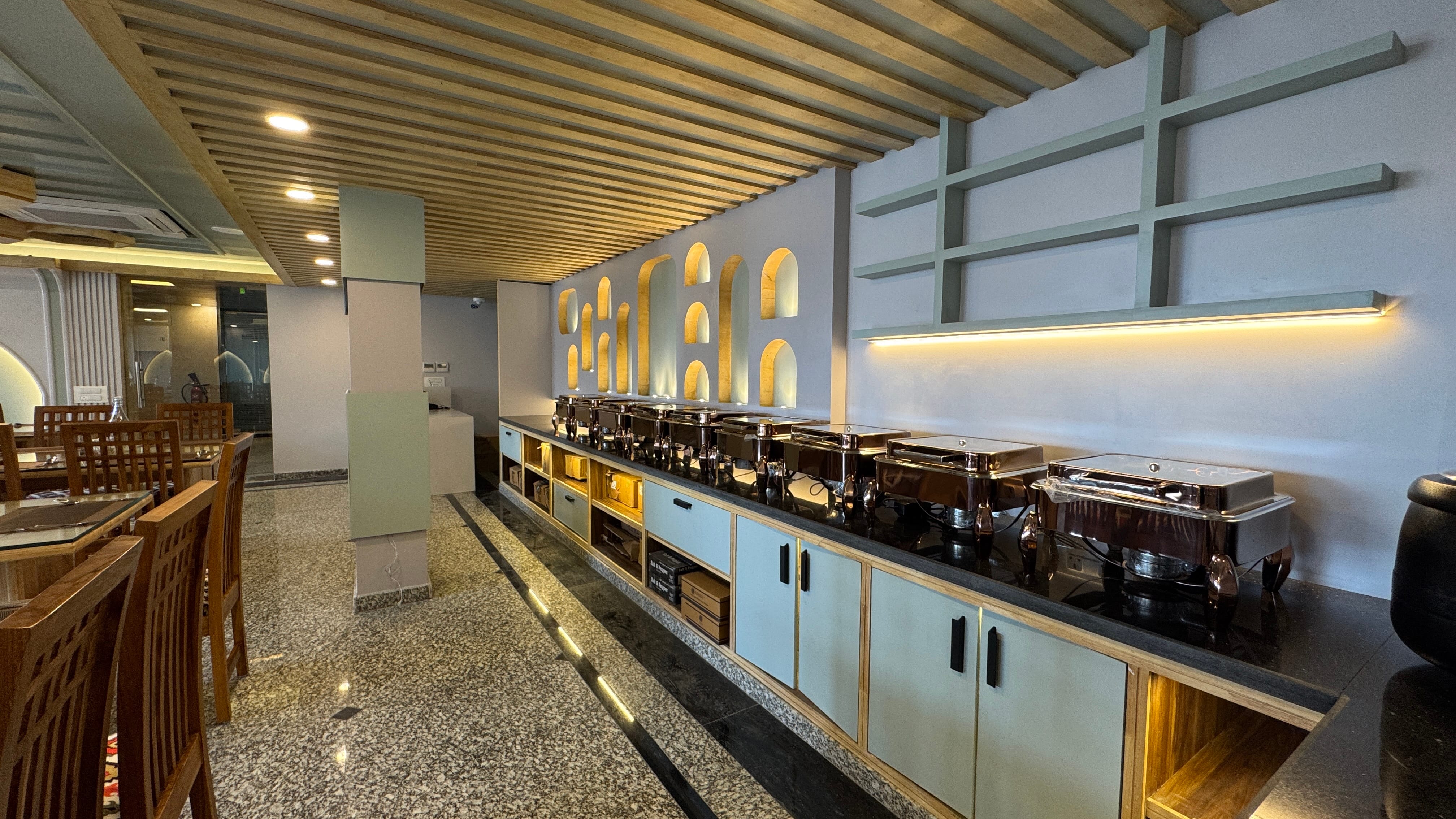 Buffet counter with chafing dishes and decorative arch wall at Emroz by Kings Resort